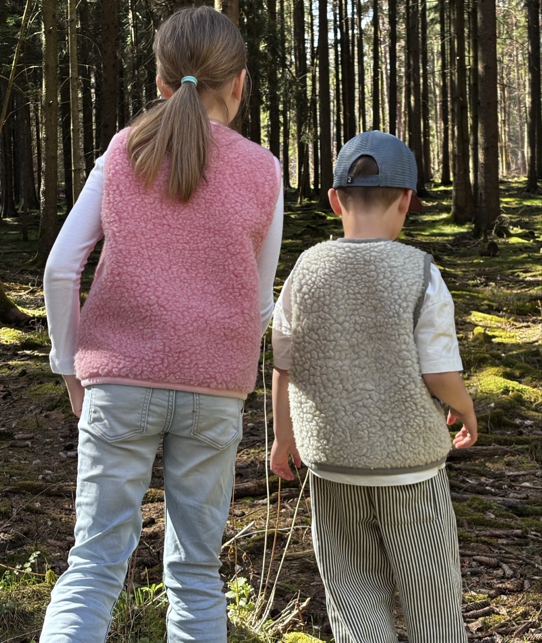 Zwei Kinder in Wollwesten aus Merinowolle im Wald